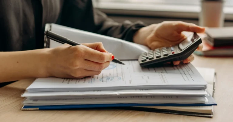 účetnictví od profesionála - ruce s kalkulačkou atužkou nad šanonem účtů